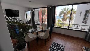 un soggiorno con tavolo e sedie e una grande finestra di Departamento antiguo frente al mar a Iquique