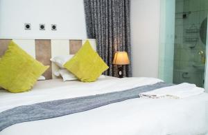 a bedroom with a white bed with yellow pillows at Suit 360 Abuja in Abuja