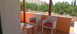 a balcony with two chairs and a table and a window at Spring studio in Egina