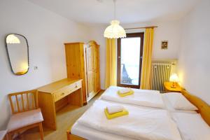 Un dormitorio con dos camas y un escritorio y un espejo. en Alpenzauber, en Bernau am Chiemsee