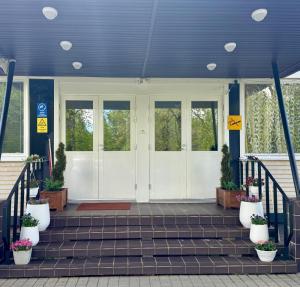 a front porch with white doors and potted plants at Hotel Ilomantsi North Star in Ilomantsi