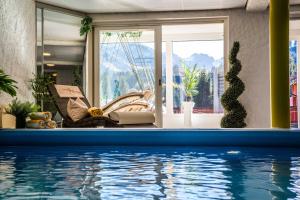 uma casa com piscina em frente a uma janela em Alpenhotel DAS KÜREN em Hirschegg