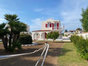 a white house with red windows and a palm tree at Villa Peonia Luxury in Bisceglie