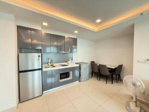 a kitchen with a refrigerator and a table with chairs at arcadia beach continental 2 bedrooms apartment in Ban Nong Chaeng