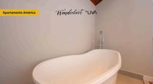 a white tub in a bathroom with a sign on the wall at WANDERLUST Experience Hotel in Campos do Jordão