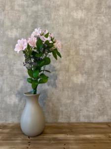 a white vase with pink flowers in it on a table at Hotel Quinta Solera in Oviedo +44 photos