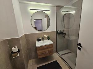 ein Badezimmer mit Waschbecken und Dusche mit Spiegel in der Unterkunft Alezzi Odyssey Mamaia Nord II - Parcare Inclusa in Mamaia Nord – Năvodari + 7 Fotos