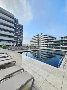 einen Pool mit Liegestühlen und zwei Gebäuden in der Unterkunft Alezzi Odyssey Mamaia Nord II - Parcare Inclusa in Mamaia Nord – Năvodari