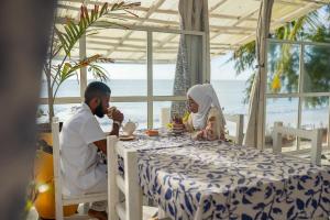 Ein Mann und eine Frau sitzen an einem Tisch in der Unterkunft ZAN Orient Beach Hotel in Bwejuu + 70 Fotos