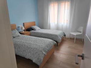 a small bedroom with two beds and a chair at Apartamento La Casica Beach Poniente in Águilas