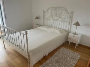 a bedroom with a white bed and a night stand at Casa da Foz do arelho in Nadadouro