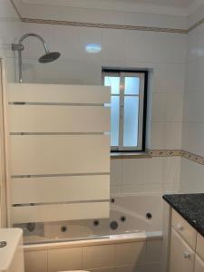 a white bathroom with a tub and a window at Casa da Foz do arelho in Nadadouro