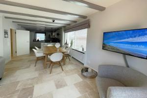 un salon avec une table et une télévision au mur dans l'établissement Ferienwohnung Goede Tiid, à Tinnum