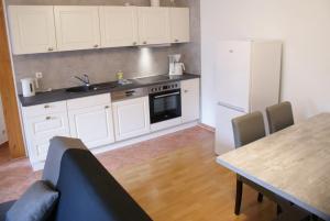 a kitchen with white cabinets and a table and a refrigerator at Heimkehr - ABC302 in Wismar