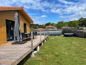 a wooden deck with an umbrella on a house at Villa le Cap in Lit-et-Mixe