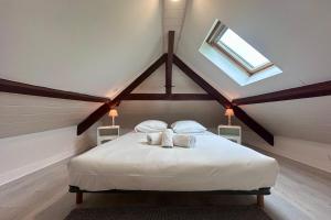 Schlafzimmer mit einem weißen Bett und einem Dachfenster in der Unterkunft Maison de Perpezac - Jardin & Clim - 7 personnes - Perpezac-le-Noir in Perpezac-le-Noir