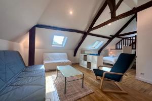 Zimmer im Dachgeschoss mit einem Bett, einem Sofa und einem Tisch in der Unterkunft Maison de Perpezac - Jardin & Clim - 7 personnes - Perpezac-le-Noir in Perpezac-le-Noir