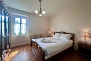 ein Schlafzimmer mit einem Bett mit weißen Laken und einem Fenster in der Unterkunft Maison de Perpezac - Jardin & Clim - 7 personnes - Perpezac-le-Noir in Perpezac-le-Noir