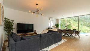 a living room with a large couch and a television at Elysium by LovelyStay in São Vicente