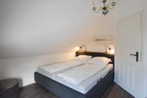 un lit avec des draps blancs et des oreillers dans une chambre dans l'établissement Ferienhaus Erika, à Tinnum