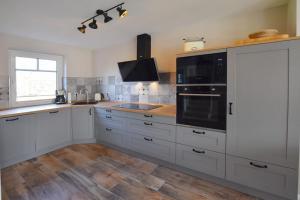 une cuisine avec des armoires blanches et un appareil noir dans l'établissement Ferienhaus Erika, à Tinnum