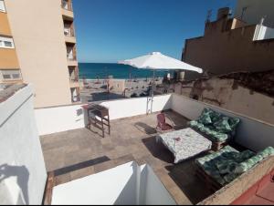 a balcony with a couch and an umbrella and the beach at Apartamento cerca del mar in Vinarós