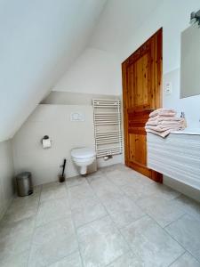 a bathroom with a toilet and a wooden door at Strandperle in List