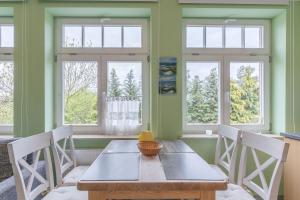 a dining room with a table and chairs and windows at Haus Tarnewitz, Ferienwohnung 06 in Tarnewitz