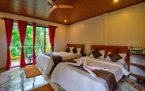 a bedroom with two beds and a window at La Roca Inn in Assagao +24 photos