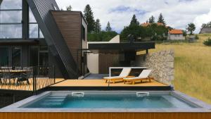 a swimming pool with two chairs and a house at Euphoria - luxury villa in Vlasic