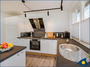a kitchen with white cabinets and a bowl of fruit on the counter at Fischerdorf Zirchow Seebär in Zirchow