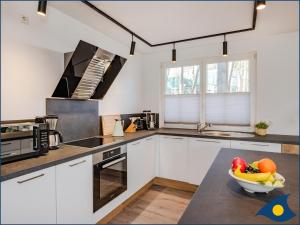 a kitchen with white cabinets and a bowl of fruit on a table at Fischerdorf Zirchow Seebär in Zirchow