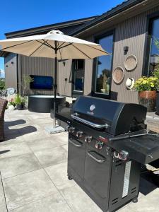 a grill with an umbrella on a patio at Enebolig på Nesbrygga in Nesbrygga