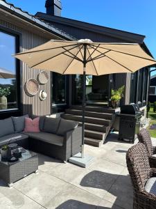 a patio with a couch and an umbrella at Enebolig på Nesbrygga 