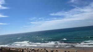 eine Gruppe von Menschen, die an einem Strand in der Nähe des Ozeans stehen in der Unterkunft Bel appartement centre Asilah proche de la mer in Aïn Harrouda
