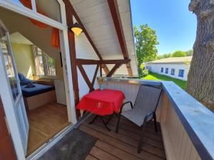 Un pequeño porche con una mesa roja y una silla. en Heringsdorf, Residenz Inselliebe - EZ, en Heringsdorf 9 fotos más