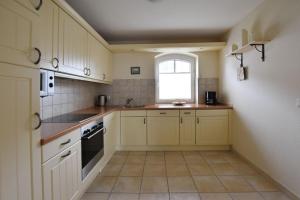 eine Küche mit weißen Schränken und einem Fenster in der Unterkunft Ferienhaus Silwai 20b in Tinnum