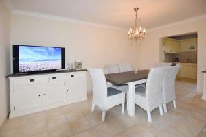 ein Esszimmer mit einem Tisch mit Stühlen und einem Fernseher in der Unterkunft Ferienhaus Silwai 20b in Tinnum