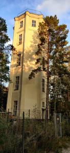 ein hohes Gebäude mit einem Baum davor in der Unterkunft Wasserturm Spreewitz in Spreewitz