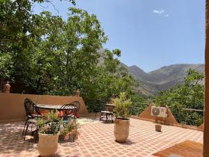 un patio con tavolo e sedie con montagne sullo sfondo di Riad Atlas Garden a Imlil