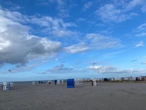 Una playa con algunas tiendas de campaña y gente volando cometas. en Ferienhaus Nordlicht, en Carolinensiel