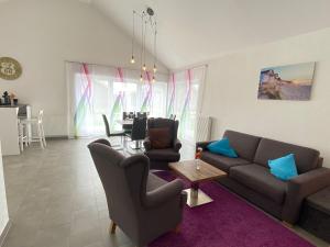 un soggiorno con un divano, sedie e un tavolo di Ferienhaus Fasanen Nest a Sehestedt