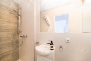 Un baño blanco con lavabo y ducha. en Haus Monika, en Helgoland