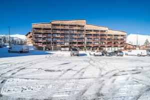 a snow covered parking lot in front of a hotel at Le repaire des mouflons 1500 in Taninges