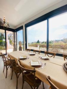 ein Esszimmer mit einem Tisch und einigen Fenstern in der Unterkunft Villa con piscina by MO in Málaga