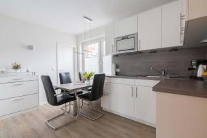 a kitchen with white cabinets and a table and chairs at MaJa in Norderney