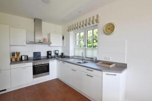 a kitchen with white cabinets and a clock on the wall at Ferienhaus Helen in Morsum