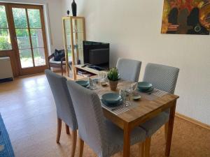 a dining room table with chairs and a television at Ferienwohnungen im Feriendorf Reichenbach Nr 9 in Nesselwang