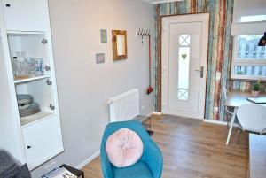 een woonkamer met een blauwe stoel en een tafel bij Lütt Hus an de See Ferienwohnung in Niendorf