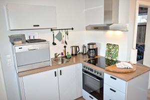 een keuken met witte kasten en een kookplaat oven bij Lütt Hus an de See Ferienwohnung in Niendorf